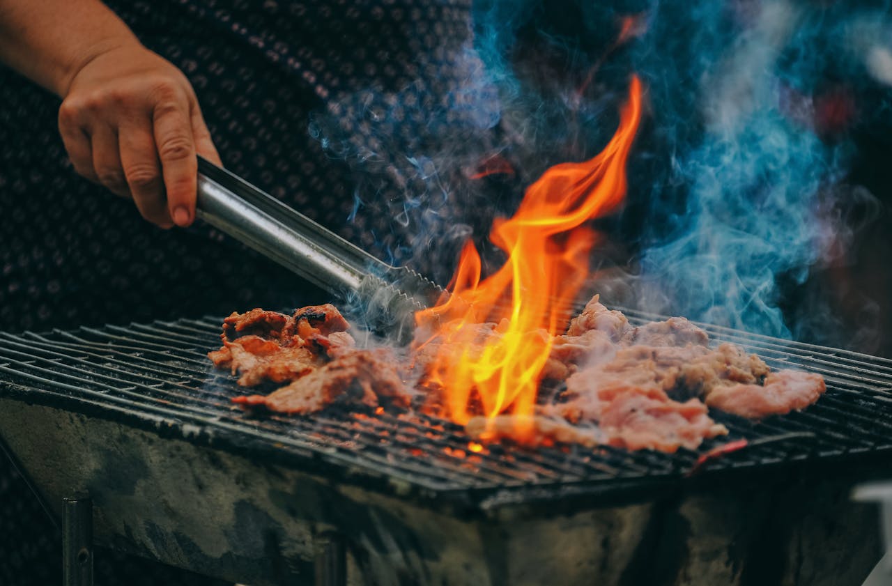 Home Close-up of grilling meat with vibrant flames and smoky aura, showcasing outdoor cooking.