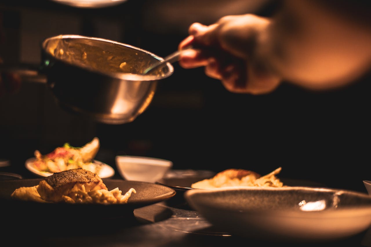 The Art of Drawing Readers In: Your attractive post title goes here Gourmet dish being plated by a chef in a dimly lit restaurant's kitchen.