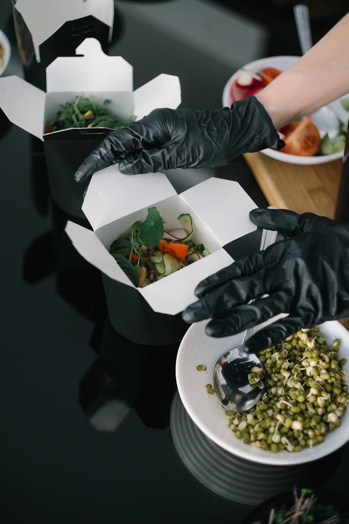 Crafting Captivating Headlines: Your awesome post title goes here Gloved hands preparing fresh salad takeout in eco-friendly containers for delivery.